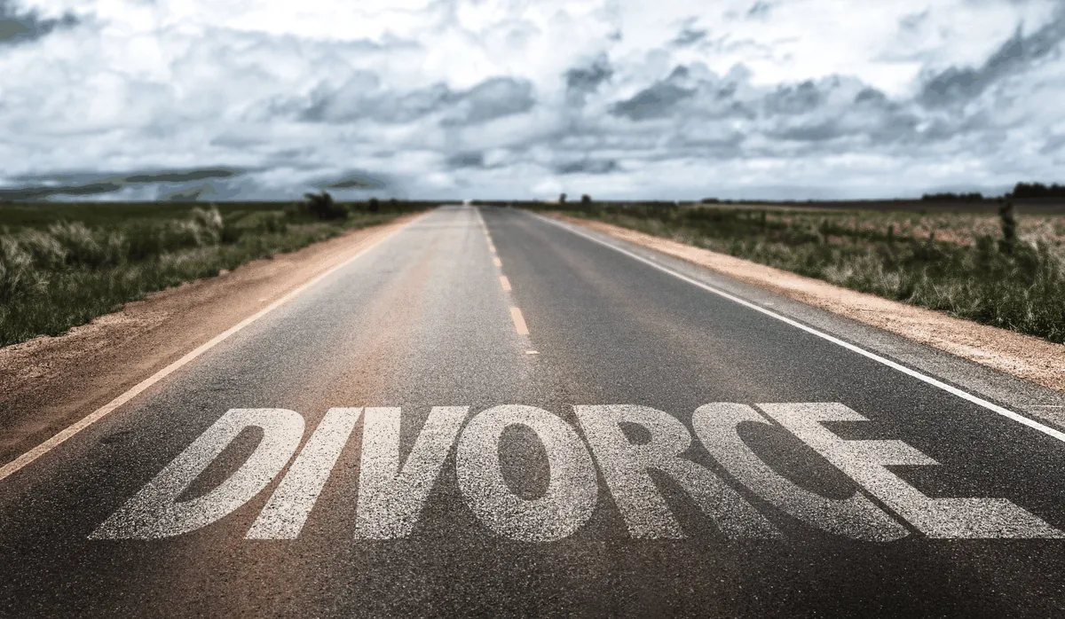 A long open road with the word DIVORCE painted on the asphalt